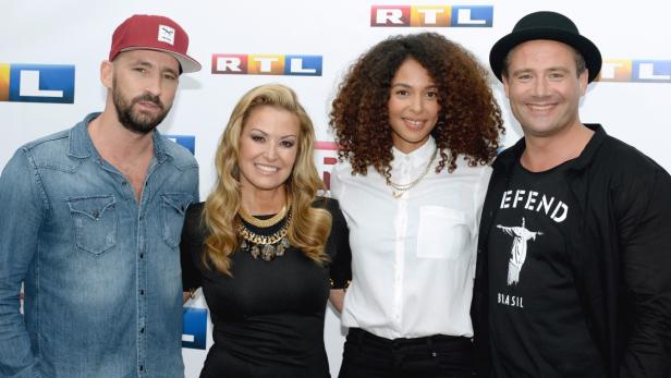 Vier Personen posieren vor einem RTL-Logo für ein Gruppenfoto.