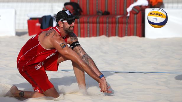 Ein Beachvolleyballspieler baggert einen Mikasa-Ball im Sand.