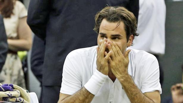 Roger Federer sitzt mit den Händen vor dem Gesicht auf der Bank.