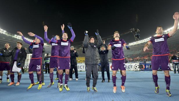 Eine Fußballmannschaft jubelt auf dem Spielfeld mit erhobenen Armen.