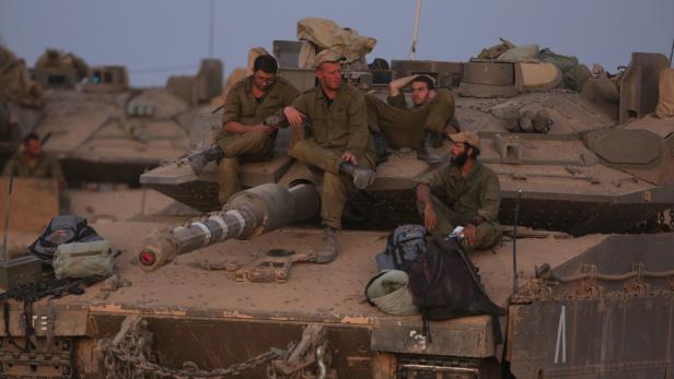 Soldaten sitzen auf Panzern und ruhen sich aus.
