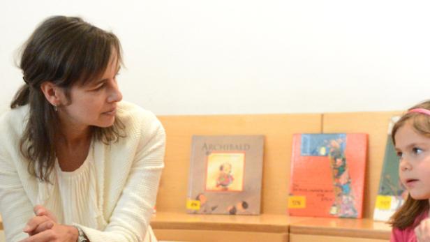 Eine Frau liest zwei kleinen Mädchen aus einem Buch vor.