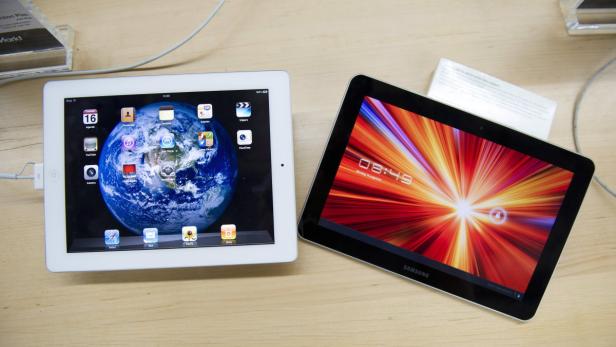Ein Apple iPad und ein Samsung Tablet liegen nebeneinander auf einem Tisch.