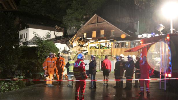 Einsatzkräfte vor dem beschädigten Haus.