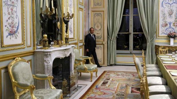 François Hollande geht durch einen opulenten Raum mit goldenen Akzenten.