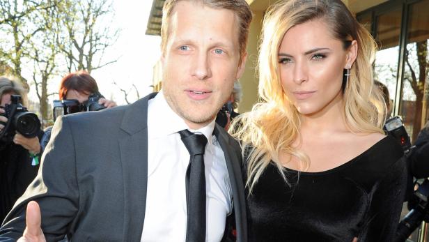 Ein Mann im Anzug und eine Frau in einem schwarzen Kleid posieren für Fotografen.