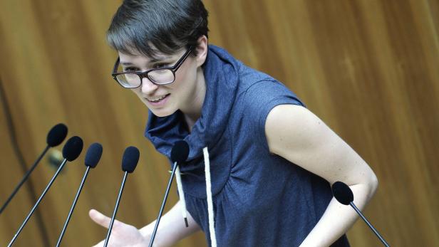 Eine Frau mit Brille spricht vor mehreren Mikrofonen.