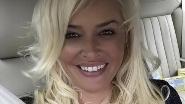 Eine Frau mit blonden, gewellten Haaren lächelt in die Kamera.