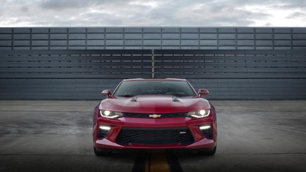 Ein roter Chevrolet Camaro steht vor einer grauen Wand.