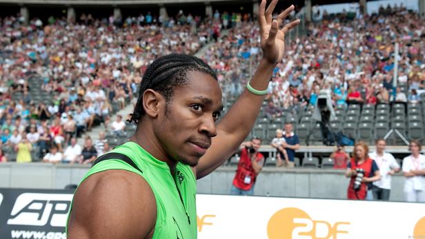 Ein Leichtathlet winkt vor einer Zuschauertribüne.