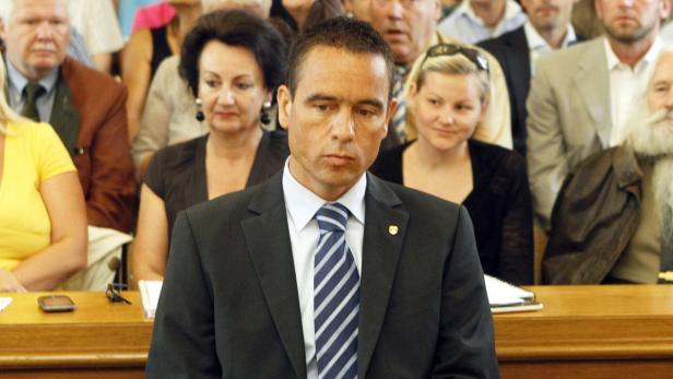 Ein Mann im Anzug sitzt vor einer Gruppe von Menschen.