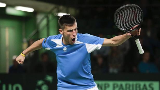 Ein Tennisspieler jubelt mit erhobener Faust und Tennisschläger.