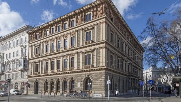 Ein Eckgebäude mit aufwendiger Fassade in einer Wiener Stadtlandschaft.
