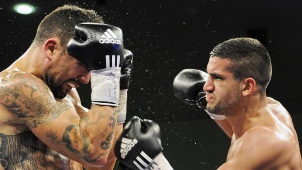 Zwei Boxer im Ring, einer schlägt den anderen mit einem Boxhandschuh ins Gesicht.