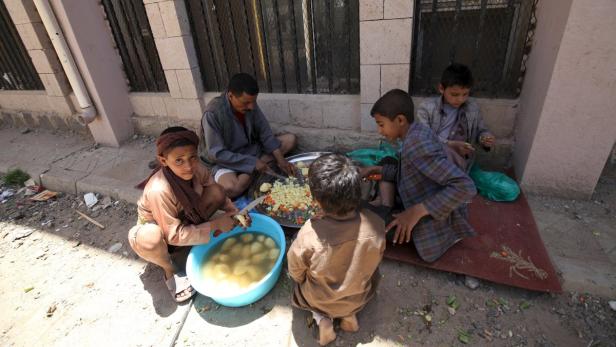 Eine Gruppe von Menschen sitzt im Freien und bereitet Gemüse zu.