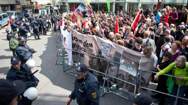 Eine Demonstration mit Menschen, Transparenten und einer Reihe Polizisten.