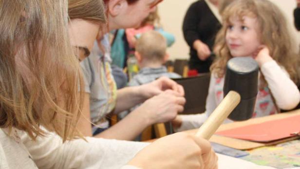 Handgefertigte dünne gebundene Kunstbüchlein: Erst nageln die Kinder Löcher durch die Seiten. Durch die ziehen sie die Nadeln mit Wollfäden - Buchbinden im wahrsten Sinn des Wortes