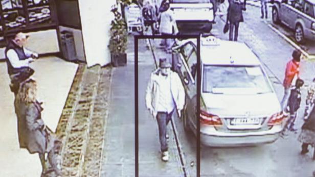 Überwachungsaufnahme einer belebten Straße mit einem Mann im Vordergrund.