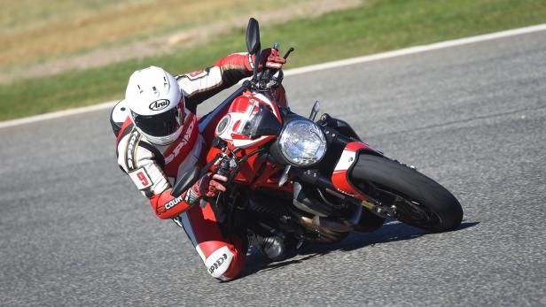 Ein Motorradfahrer in roter Lederkombi fährt eine rote Ducati auf einer Rennstrecke.