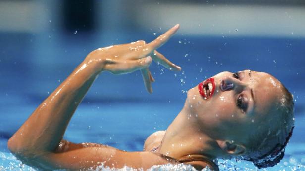 Eine Synchronschwimmerin während einer Aufführung im Wasser.
