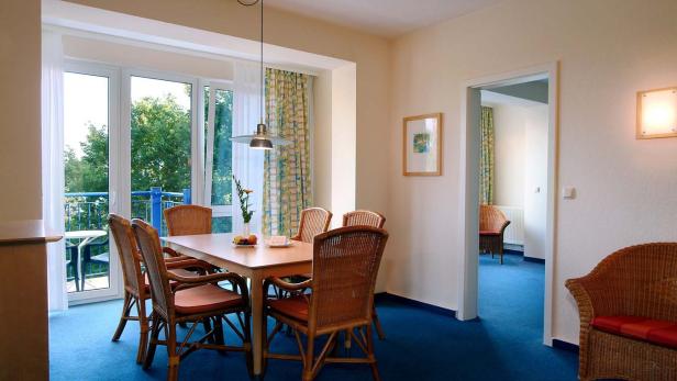 Ein Esszimmer mit einem Holztisch und Korbstühlen unter einer Hängelampe.