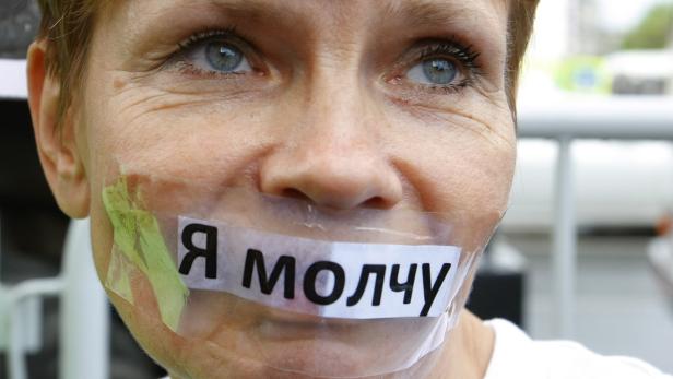 Eine Frau hat ein Klebeband mit der russischen Aufschrift „Ich schweige“ über dem Mund.
