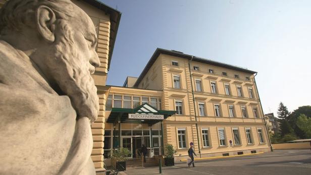 Das Rudolfinerhaus in Wien, teilweise verdeckt von einer Statue im Vordergrund.