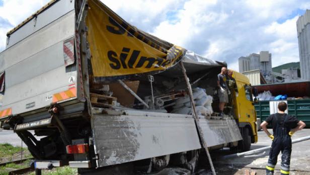 Ein beschädigter LKW mit gerissener Plane steht auf einem Gelände.