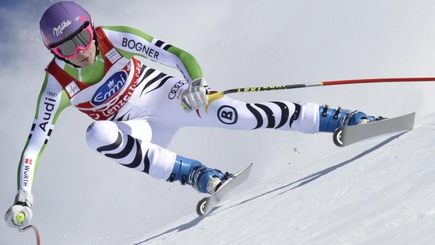 Eine Skirennläuferin in voller Montur fährt einen Hang hinunter.