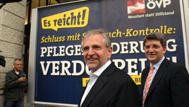 Zwei Männer stehen vor einem Wahlplakat der ÖVP mit der Aufschrift „Es reicht!“.