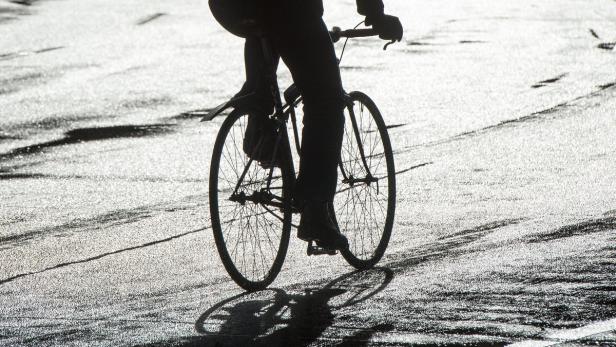 Eine Person fährt mit einem Fahrrad auf einer glänzenden Oberfläche.