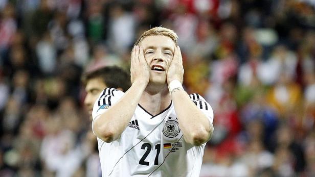 Ein deutscher Fußballspieler mit schmerzverzerrtem Gesicht hält die Hände vor das Gesicht.