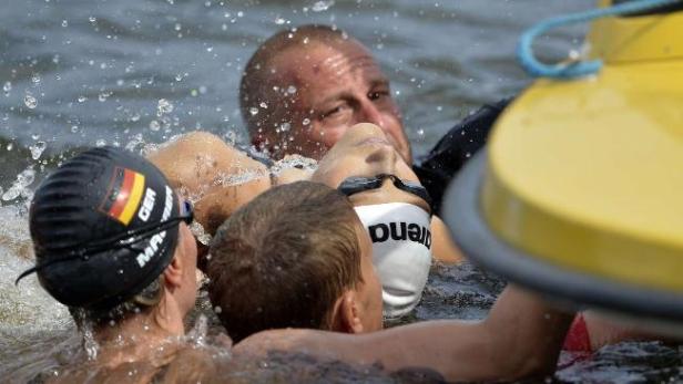 Ein Schwimmer wird im Wasser von Rettungskräften unterstützt.