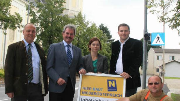 Eine Gruppe von Personen steht vor einem Schild in Obersiebenbrunn, Niederösterreich.