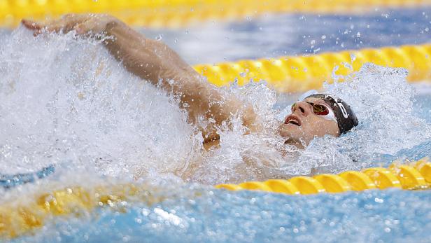 Ein Schwimmer mit Schwimmbrille beim Rückenschwimmen im Schwimmbecken.