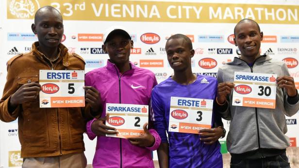 Vier Läufer des Vienna City Marathon 2016 präsentieren ihre Startnummern.