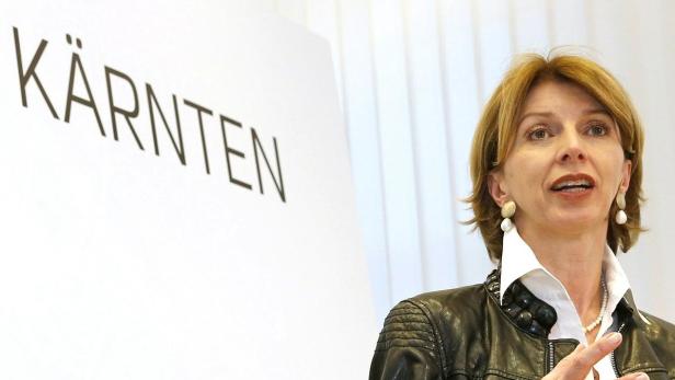 Eine Frau spricht vor einem Schild mit der Aufschrift „Kärnten“.