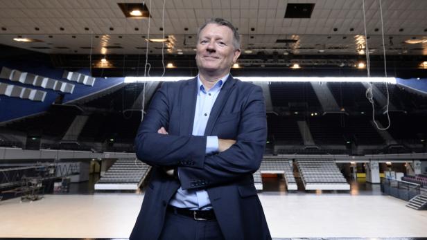 Ein Mann mit verschränkten Armen steht in einer leeren Arena.