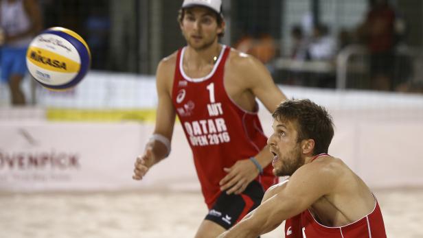 Zwei Beachvolleyballspieler bei einem Spiel im Sand.