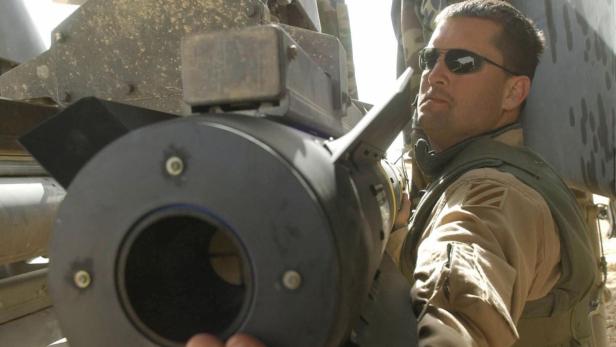 Ein Soldat mit Sonnenbrille hantiert mit einer Rakete.