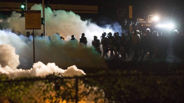 Polizisten in Schutzausrüstung stehen im Rauch einer Rauchbombe.