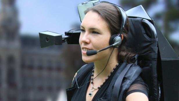 Eine Frau trägt ein Headset und eine am Rücken befestigte Kameraanlage.