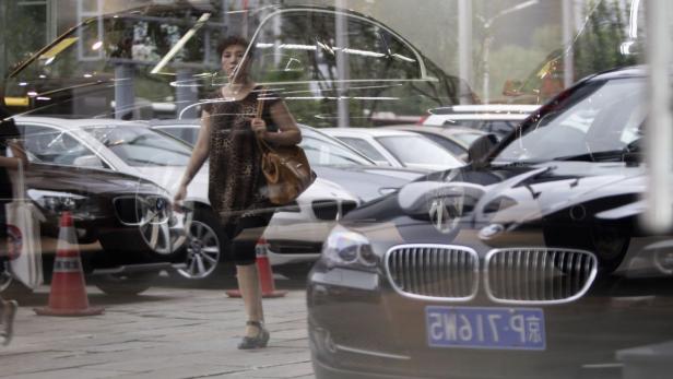 Eine Frau geht an geparkten Autos vorbei.