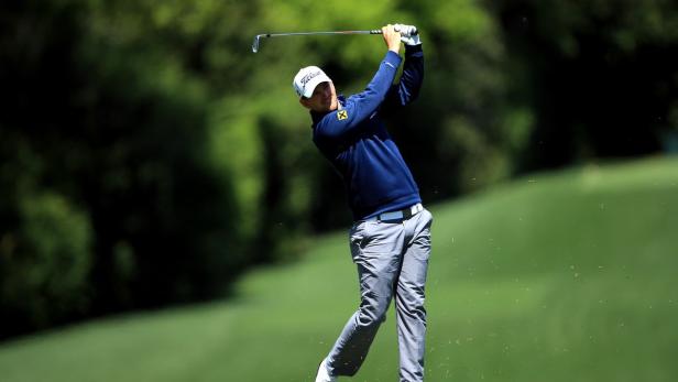 Ein Golfspieler schwingt seinen Schläger auf einem grünen Golfplatz.