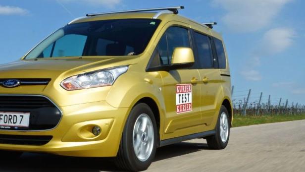 Ein goldener Ford Transit fährt auf einer Landstraße entlang eines Weinbergs.
