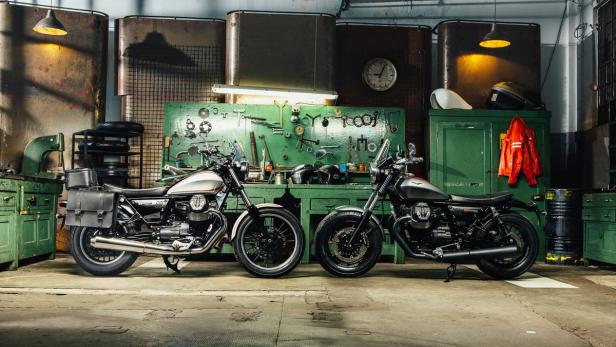 Zwei Moto Guzzi Motorräder stehen in einer Werkstatt vor einer Werkzeugwand.