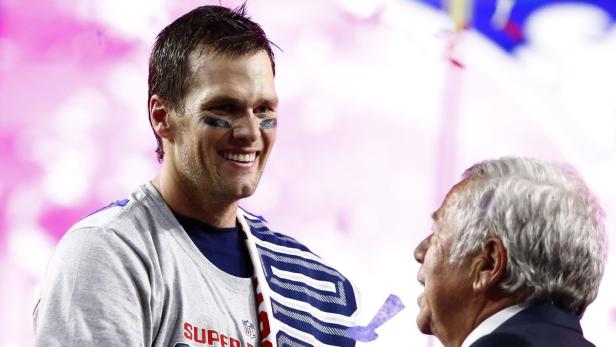 Tom Brady lächelt mit Schminke unter den Augen, während er mit einer anderen Person spricht.