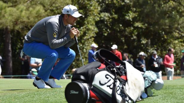 Ein Golfspieler hockt auf dem Grün und betrachtet den Platz.