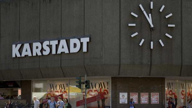 Das Karstadt-Gebäude mit einer großen Uhr an der Fassade und Passanten davor.