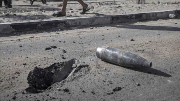 Eine nicht explodierte Granate liegt auf einer zerstörten Straße.